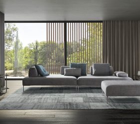 divano moderno grigio tre posti in un salotto di design che si affaccia su un giardino da un ampia finestra che domina la stanza