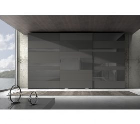 ampio armadio di design ad ante scorrevoli in una stanza minimal e semplice da cui entra un raggio di luce