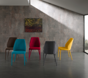 sedie di design colorate in emzzo ad una stanza grigia illuminata da un raggio di sole