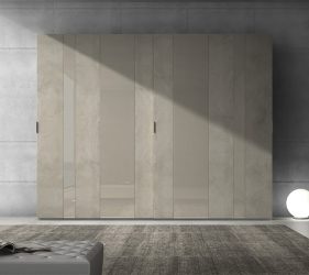 armadio effetto cemento a muro con ante apribili in un ambiente neutro e asettico con un pouf grigio