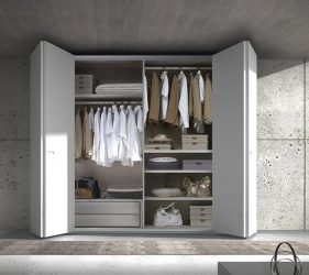 armadio bianco moderno aperto con vestiti a vista illuminato dalla luce che entra nella stanza elegante e minimal
