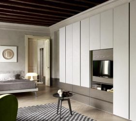 camera da letto classica con letto, poltrona, armadio a muro con tv in stanza rustica con travi in legno a vista