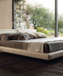 letto moderno ed elegante in pelle sospeso da terra in una stanza illuminata da ampie finestre
